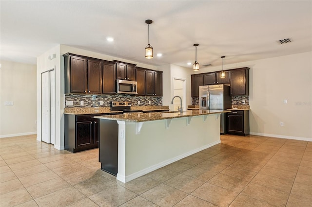 185 Hamlet Loop, Davenport, FL 33837 - kitchen with stainless steel appliances, light tile patterned floors, a breakfast bar area, decorative backsplash, and dark stone countertops