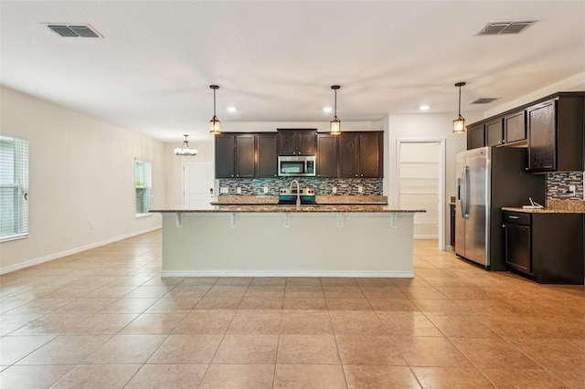 185 Hamlet Loop, Davenport, FL 33837 - kitchen with stainless steel appliances, decorative backsplash, light tile patterned floors, a breakfast bar, and recessed lighting