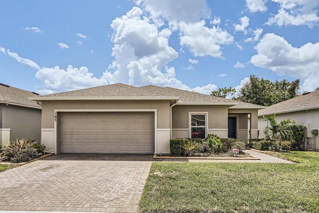 185 Hamlet Loop, Davenport, FL 33837 - prairie-style home featuring stucco siding, decorative driveway, an attached garage, a front yard, and a shingled roof