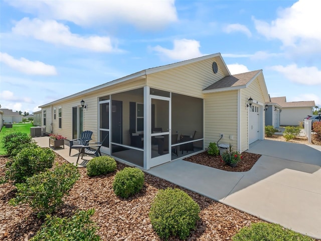 6301 Whittle Ct, The Villages, FL 32163 - rear view of house with a sunroom, an attached garage, concrete driveway, and central air condition unit