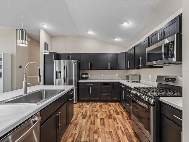 6301 Whittle Ct, The Villages, FL 32163 - kitchen featuring appliances with stainless steel finishes, a sink, vaulted ceiling, light countertops, and light wood finished floors