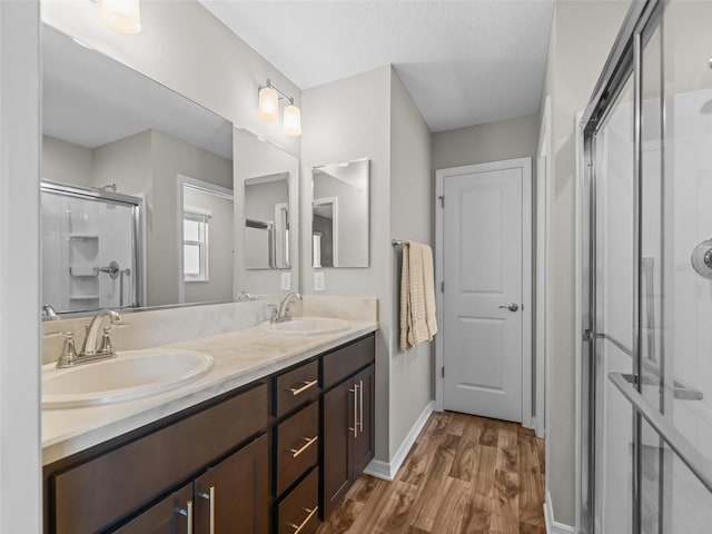 6301 Whittle Ct, The Villages, FL 32163 - bathroom featuring a shower stall, double vanity, wood finished floors, and baseboards