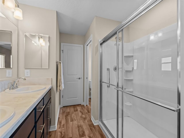 6301 Whittle Ct, The Villages, FL 32163 - full bath featuring wood finished floors, double vanity, a stall shower, and baseboards