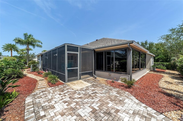 1910 Quiet Oak Ct, The Villages, FL 32162 - back of house featuring a sunroom, roof with shingles, and a patio area