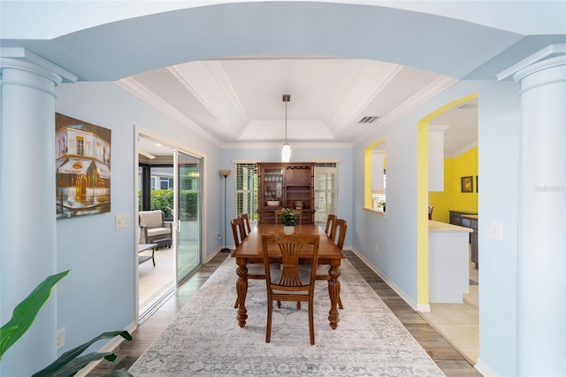 1910 Quiet Oak Ct, The Villages, FL 32162 - dining area with light wood-style floors, ornate columns, crown molding, a tray ceiling, and baseboards