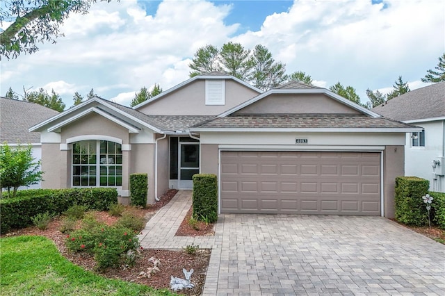 4083 Capland Ave, Clermont, FL 34711 - single story home with stucco siding, a garage, decorative driveway, and a shingled roof