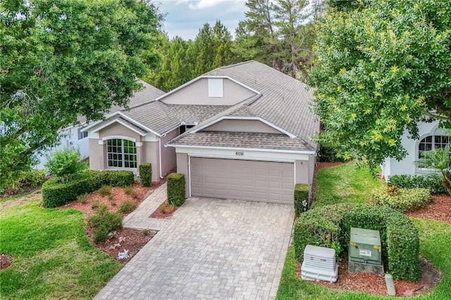 4083 Capland Ave, Clermont, FL 34711 - view of front facade with an attached garage, stucco siding, decorative driveway, roof with shingles, and a front yard