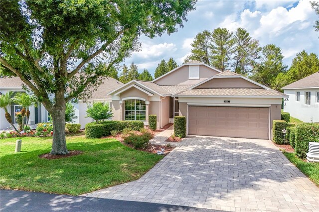4083 Capland Ave, Clermont, FL 34711 - ranch-style house with stucco siding, a front lawn, an attached garage, decorative driveway, and roof with shingles