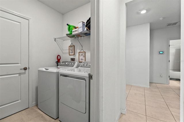 33960 Sky Blossom Cir, Leesburg, FL 34788 - laundry area featuring washer and clothes dryer, light tile patterned flooring, and baseboards