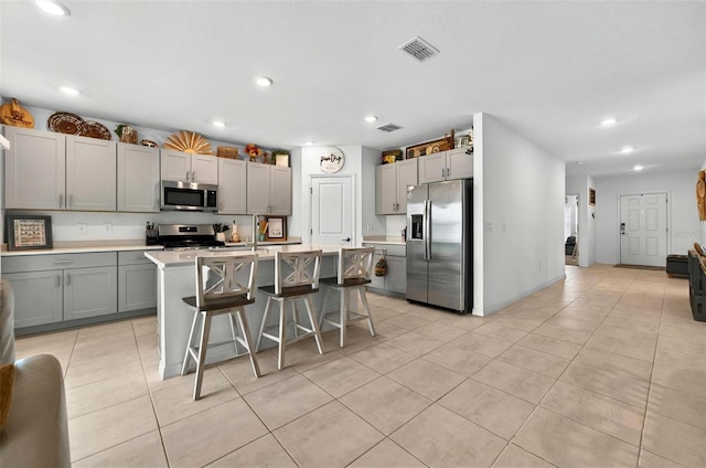 33960 Sky Blossom Cir, Leesburg, FL 34788 - kitchen featuring stainless steel appliances, gray cabinets, light tile patterned floors, a kitchen breakfast bar, and recessed lighting