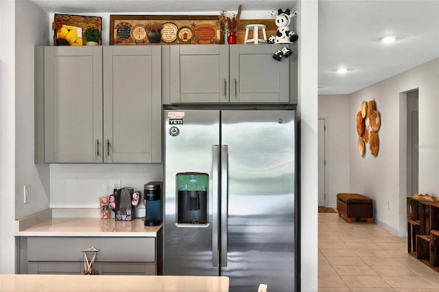 33960 Sky Blossom Cir, Leesburg, FL 34788 - kitchen with stainless steel refrigerator with ice dispenser, gray cabinetry, light tile patterned flooring, light countertops, and baseboards