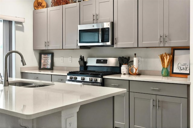 33960 Sky Blossom Cir, Leesburg, FL 34788 - kitchen with stainless steel appliances, a sink, gray cabinetry, and light stone countertops