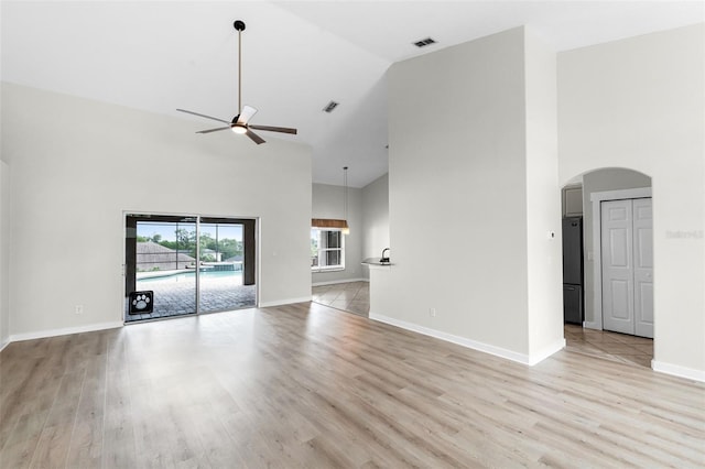 12838 Owasso Ln, Clermont, FL 34711 - unfurnished living room with high vaulted ceiling, arched walkways, ceiling fan, light wood-style floors, and baseboards