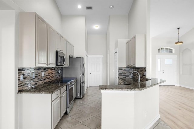 12838 Owasso Ln, Clermont, FL 34711 - kitchen with stainless steel appliances, decorative backsplash, dark stone counters, a towering ceiling, and a peninsula