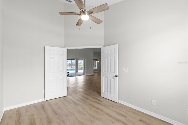 12838 Owasso Ln, Clermont, FL 34711 - empty room featuring baseboards, light wood-style flooring, a high ceiling, and ceiling fan