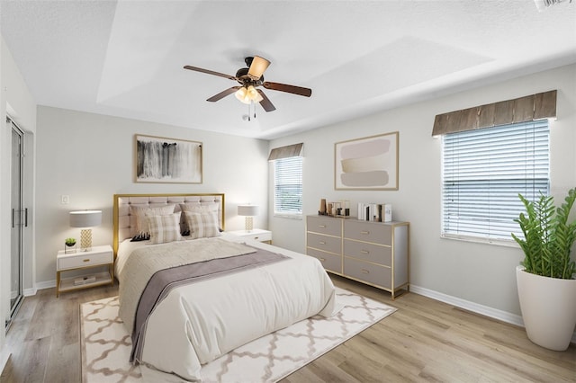 12838 Owasso Ln, Clermont, FL 34711 - bedroom featuring baseboards, light wood-style floors, a ceiling fan, and a raised ceiling