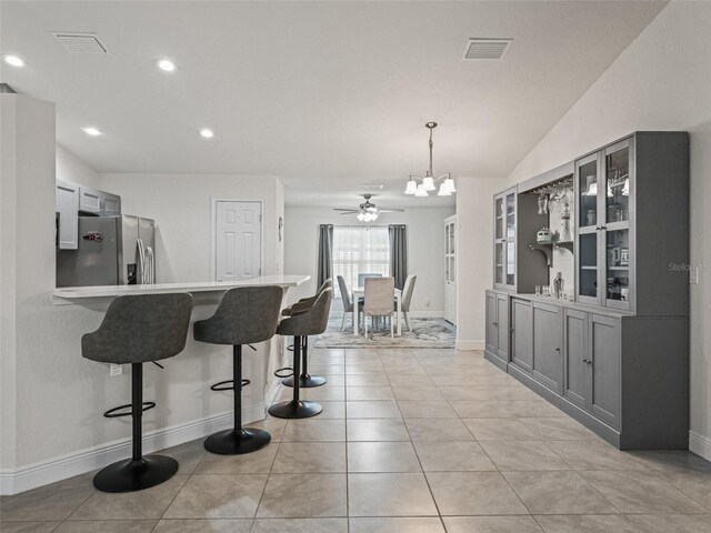 9364 SE 164th Pl, Summerfield, FL 34491 - kitchen featuring stainless steel fridge, a breakfast bar area, gray cabinetry, glass insert cabinets, and recessed lighting