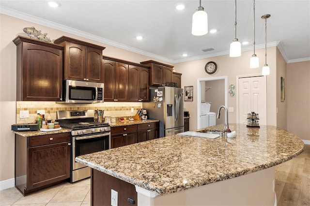 3809 Arlington Ridge Blvd, Leesburg, FL 34748 - kitchen with stainless steel appliances, washer and clothes dryer, an island with sink, dark brown cabinets, and decorative backsplash