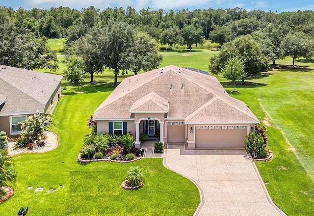3809 Arlington Ridge Blvd, Leesburg, FL 34748 - view of front facade featuring a garage, concrete driveway, stucco siding, a front yard, and roof with shingles