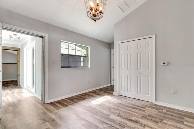 10330 Dwights Rd, Clermont, FL 34714 - unfurnished bedroom with a chandelier, wood finished floors, baseboards, a closet, and vaulted ceiling