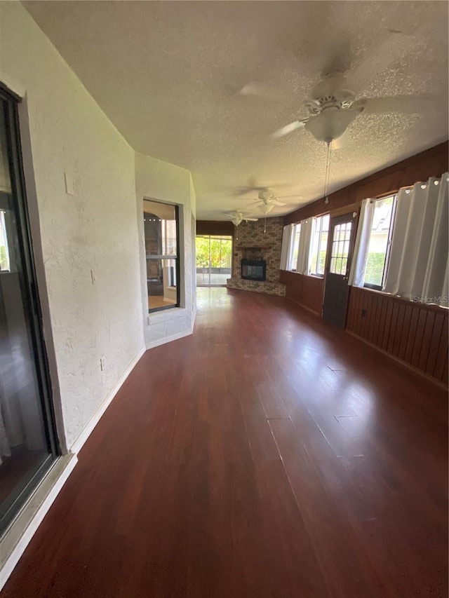 901 Baylor Dr, Deltona, FL 32725 - unfurnished living room with ceiling fan, a fireplace, dark wood finished floors, a textured ceiling, and baseboards