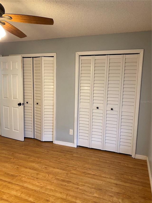 901 Baylor Dr, Deltona, FL 32725 - unfurnished bedroom featuring light wood-style floors, baseboards, two closets, a textured ceiling, and ceiling fan