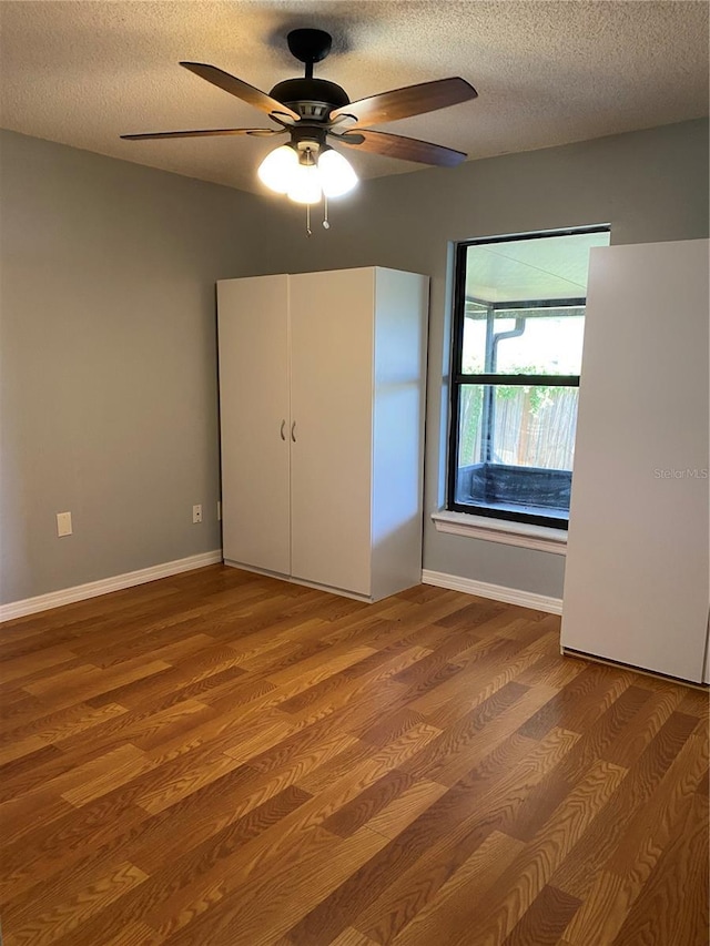 901 Baylor Dr, Deltona, FL 32725 - unfurnished bedroom with wood finished floors, a textured ceiling, baseboards, and a ceiling fan