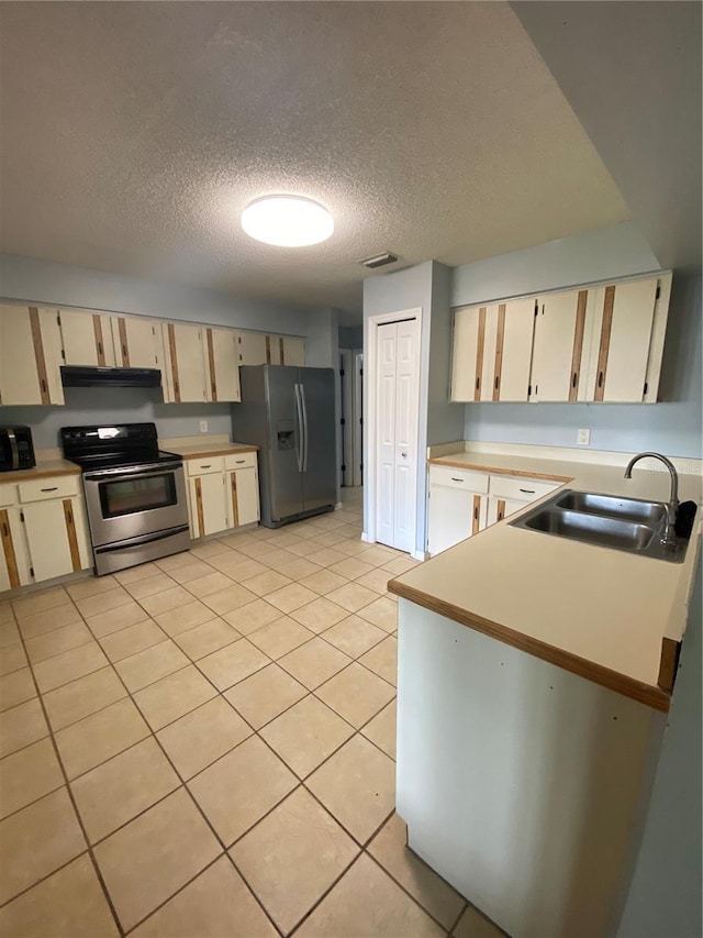 901 Baylor Dr, Deltona, FL 32725 - kitchen with appliances with stainless steel finishes, a sink, light countertops, a textured ceiling, and light tile patterned flooring