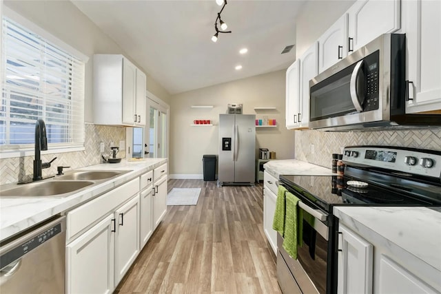 40140 Palm St, Lady Lake, FL 32159 - kitchen featuring stainless steel appliances, a sink, tasteful backsplash, white cabinets, and vaulted ceiling