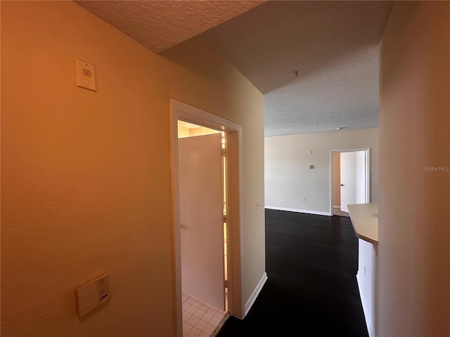 5560 Metrowest Blvd Unit 3-204, Orlando, FL 32811 - hallway featuring a textured ceiling, baseboards, and dark wood-type flooring