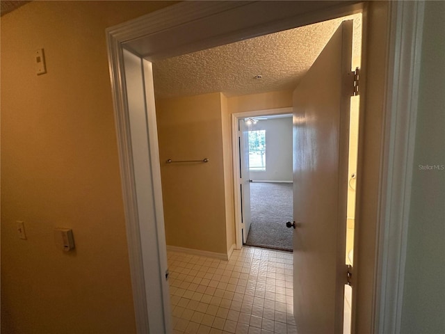 5560 Metrowest Blvd Unit 3-204, Orlando, FL 32811 - hallway featuring a textured ceiling, baseboards, and tile patterned flooring