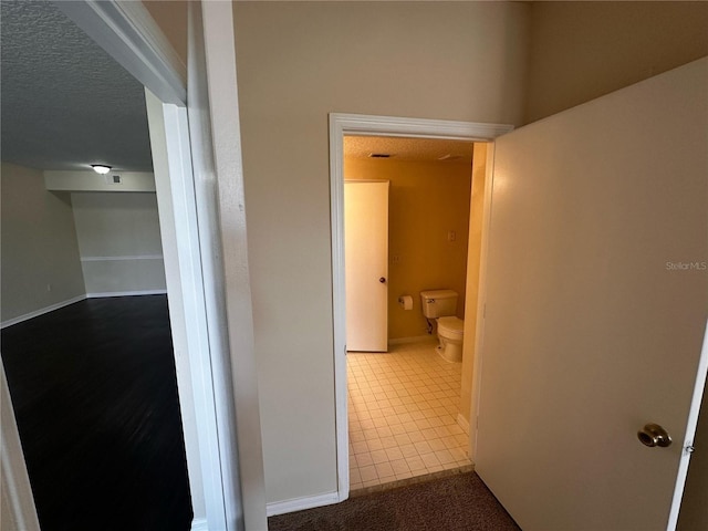 5560 Metrowest Blvd Unit 3-204, Orlando, FL 32811 - corridor featuring dark tile patterned floors, a textured ceiling, and baseboards
