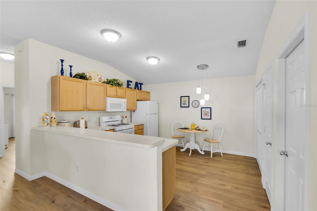 2111 Thornton Ter, The Villages, FL 32162 - kitchen featuring white appliances, light countertops, light wood finished floors, vaulted ceiling, and a peninsula