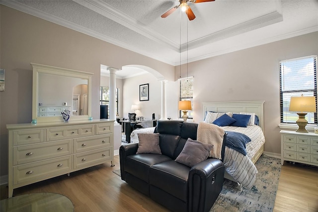 21206 Canoe Pass St, Clermont, FL 34715 - bedroom with decorative columns, arched walkways, wood finished floors, a raised ceiling, and ornamental molding