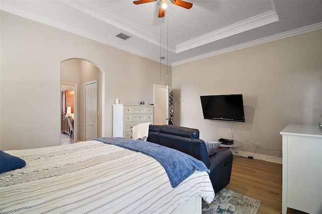 21206 Canoe Pass St, Clermont, FL 34715 - bedroom with a tray ceiling, arched walkways, wood finished floors, ornamental molding, and baseboards