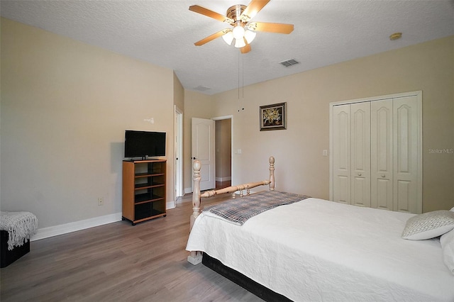 21206 Canoe Pass St, Clermont, FL 34715 - bedroom featuring wood finished floors, a closet, baseboards, a textured ceiling, and ceiling fan