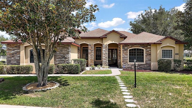 21206 Canoe Pass St, Clermont, FL 34715 - mediterranean / spanish home featuring stucco siding, stone siding, and a front lawn