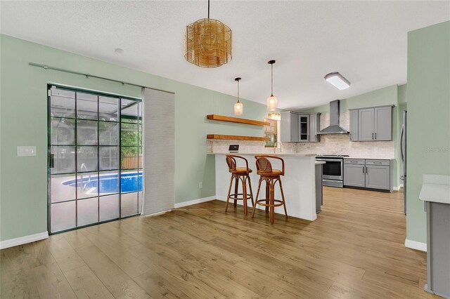 717 SE 46th Ct, Ocala, FL 34471 - kitchen featuring wall chimney exhaust hood, gray cabinets, stainless steel electric range oven, a peninsula, and decorative backsplash