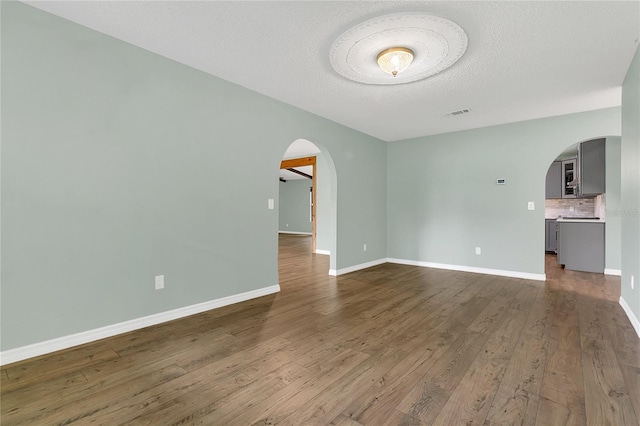 717 SE 46th Ct, Ocala, FL 34471 - spare room with arched walkways, wood finished floors, and a textured ceiling