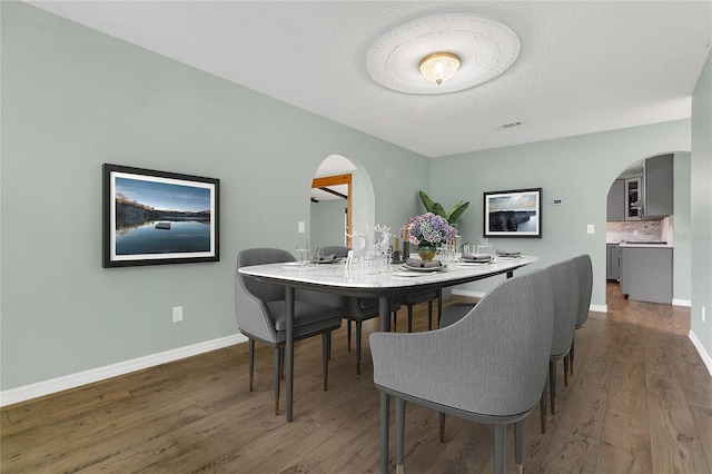 717 SE 46th Ct, Ocala, FL 34471 - dining space with arched walkways, wood finished floors, and a textured ceiling