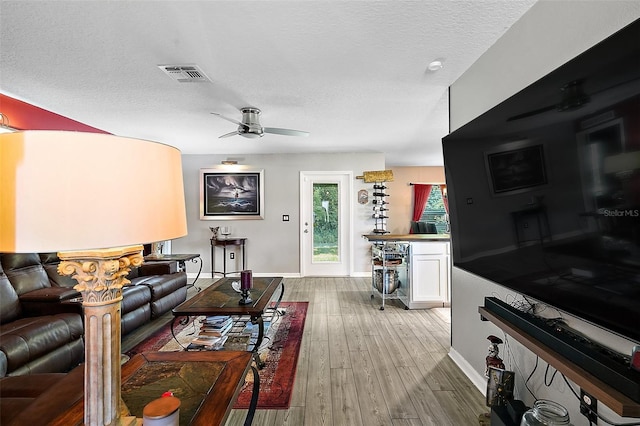 12952 Del Lago Dr, Astatula, FL 34705 - living room with ceiling fan, baseboards, light wood-style flooring, and a textured ceiling