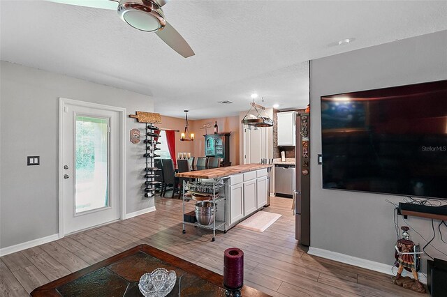 12952 Del Lago Dr, Astatula, FL 34705 - living room with light wood-type flooring, baseboards, a ceiling fan, and a textured ceiling