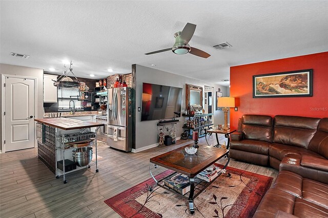 12952 Del Lago Dr, Astatula, FL 34705 - living area featuring a ceiling fan, a textured ceiling, light wood-style flooring, and baseboards