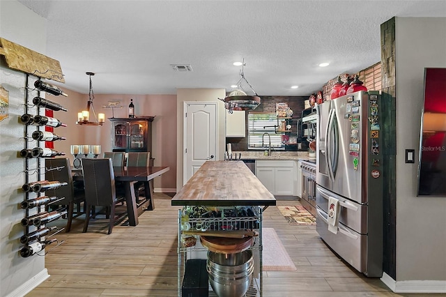 12952 Del Lago Dr, Astatula, FL 34705 - kitchen with appliances with stainless steel finishes, light wood-type flooring, white cabinets, baseboards, and a textured ceiling