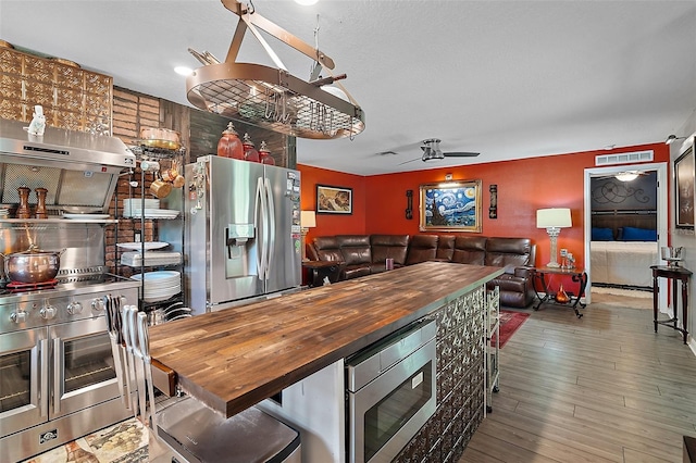 12952 Del Lago Dr, Astatula, FL 34705 - kitchen featuring appliances with stainless steel finishes, wood counters, open floor plan, wood finished floors, and ceiling fan