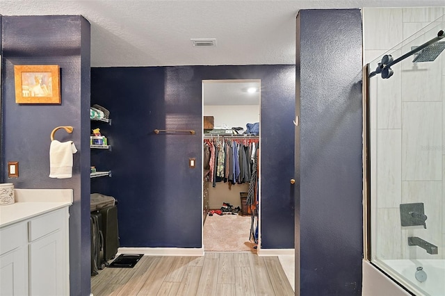 12952 Del Lago Dr, Astatula, FL 34705 - full bathroom with wood finished floors, shower / bath combination with glass door, baseboards, a spacious closet, and vanity