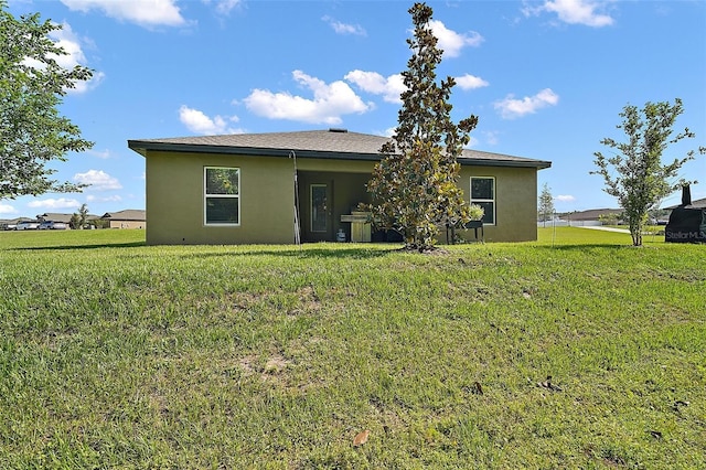 12952 Del Lago Dr, Astatula, FL 34705 - rear view of house with stucco siding and a lawn