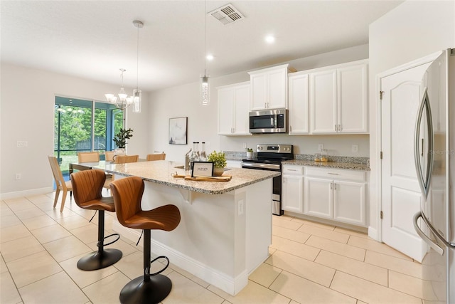 17112 Goldcrest Loop, Clermont, FL 34714 - kitchen with stainless steel appliances, a chandelier, light stone counters, a center island with sink, and a kitchen bar