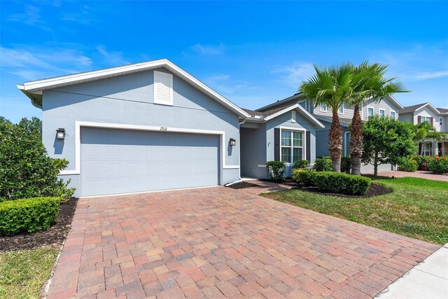 17112 Goldcrest Loop, Clermont, FL 34714 - ranch-style home with stucco siding, decorative driveway, and an attached garage