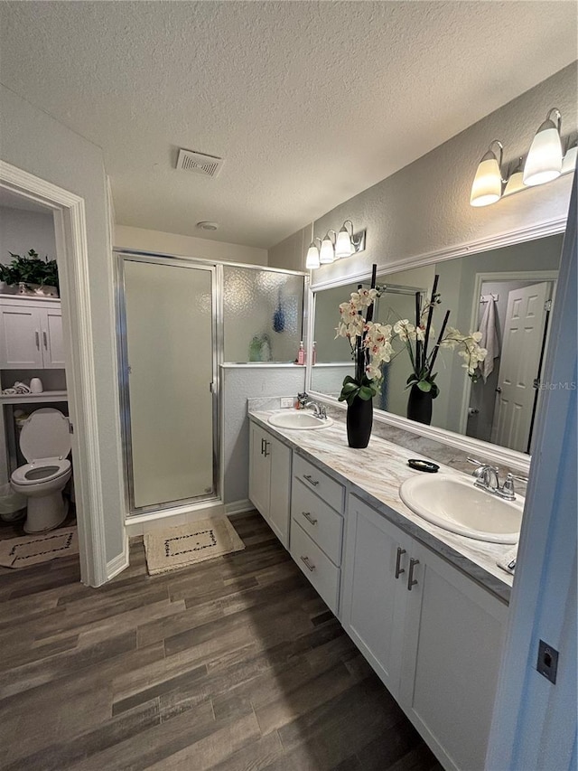 5547 SE 91st Pl, Ocala, FL 34480 - full bathroom featuring double vanity, toilet, a textured ceiling, a stall shower, and wood finished floors